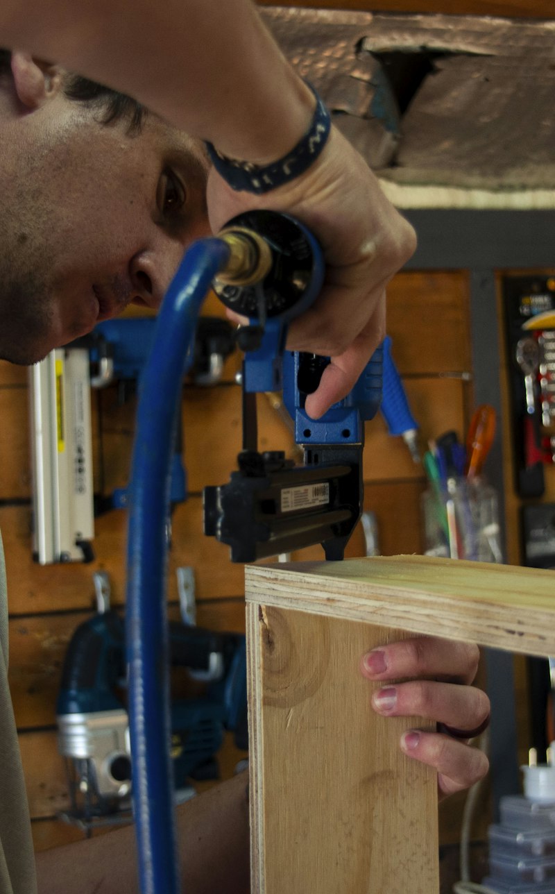 Carpintero armando una pieza de madera con clavadora en su taller